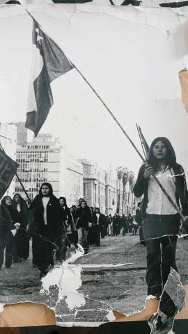 Fotografía de mujer marchando con bandera chilena